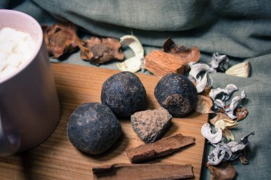 Tarçınlı doğal kakao topları ve ahşap bir standın üzerindeki diğer baharatlar. Gri arka planda marşmelovları olan pembe bir fincan kakao.