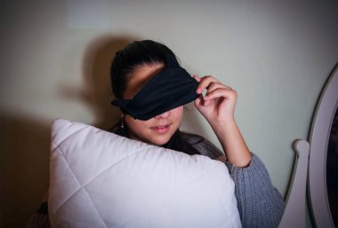 Pijama partisine hazırlanmak için yastıkla uyumak için maskeli bir kız.