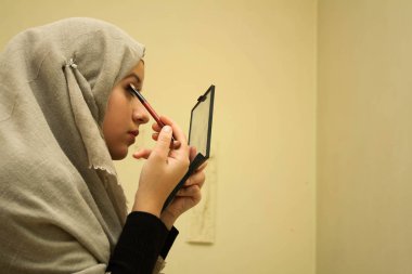 Güzel müslüman kız makyaj yapıyor.