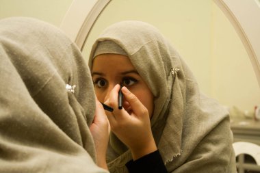 Güzel müslüman kız makyaj yapıyor.