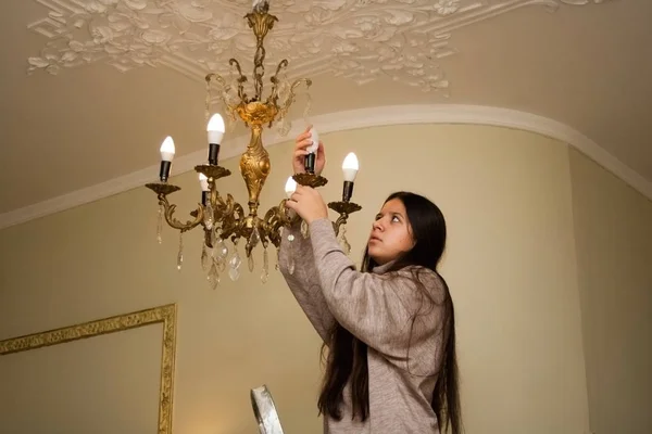 Girl changes light bulb at her home