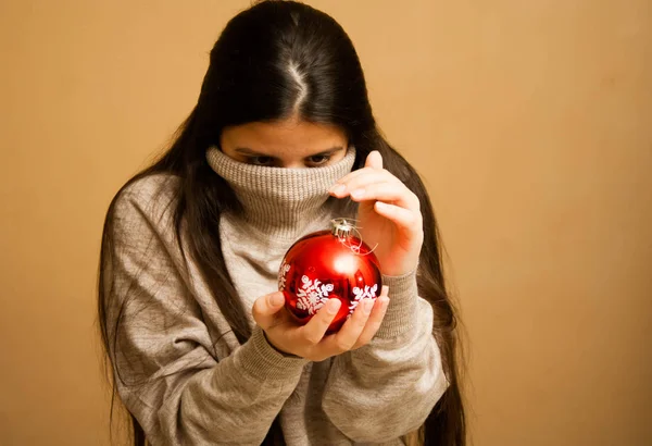 Девушка, завернутая в свитер с рождественским мячом — стоковое фото