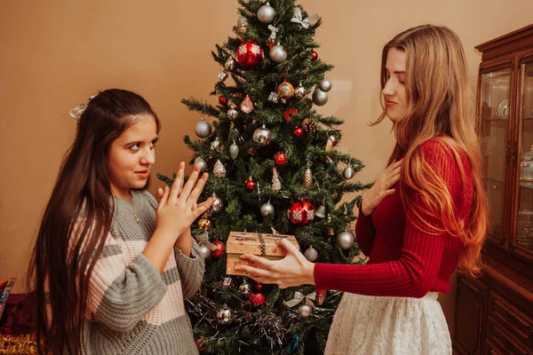 Две девушки дарят подарки возле елки — стоковое фото