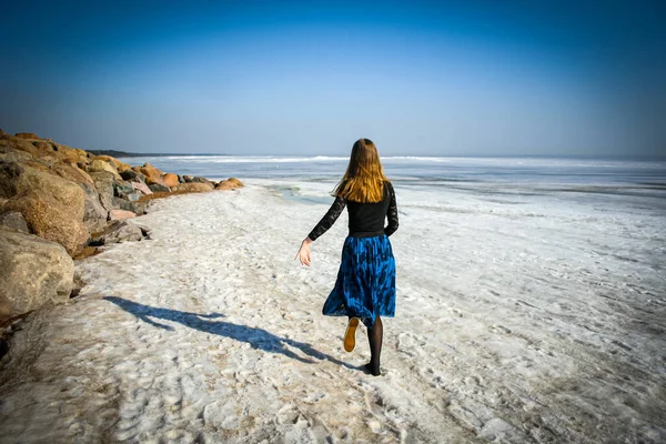 Girl walks on frozen water cover of Northern sea