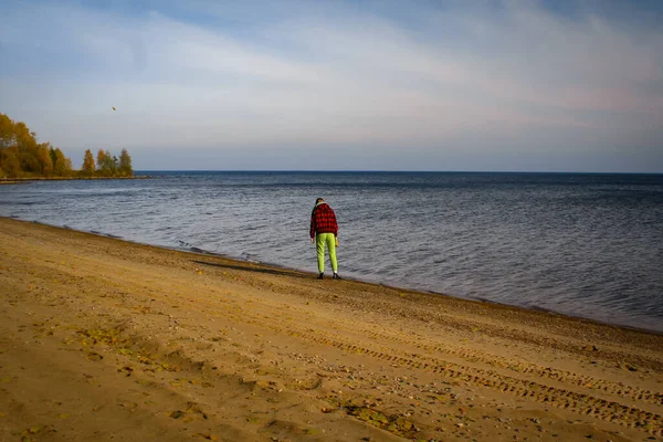 Girl stands on the sandy shore of the lake on an autumn sunny day — Stock Photo, Image