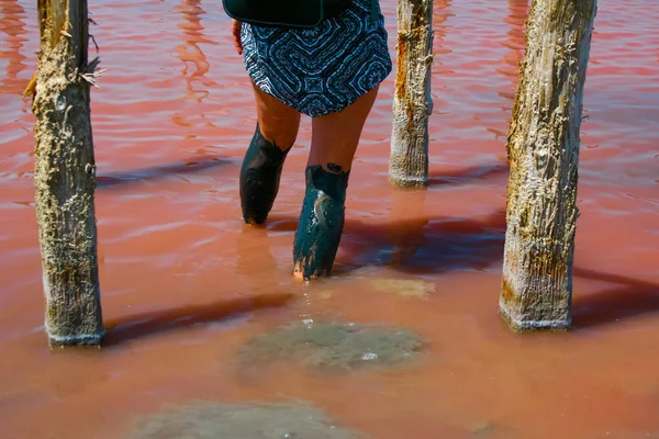 Legs of a young girl in the water of a pink salty mud lake