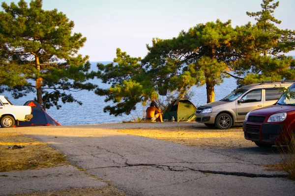 Carros e tenda em uma colina com vista para o mar na hora de ouro — Fotografia de Stock