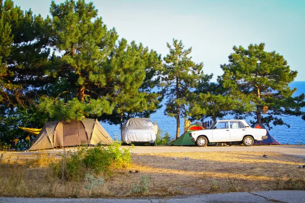 Carros e tenda em uma colina com vista para o mar na hora de ouro — Fotografia de Stock