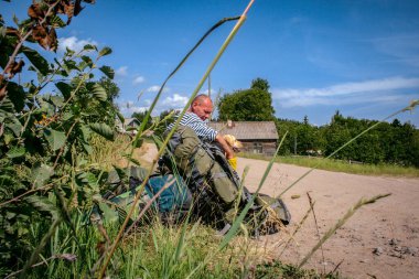 Leningrad Oblastı, Rusya - 7 Haziran 2010: Sırt çantalı bir adam güneşli bir yaz günü geçtikten sonra labrador köpeğiyle birlikte tarlada dinleniyor