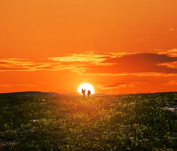 Pair tourist stay among a prairiie on a sunset background — Stock Photo, Image