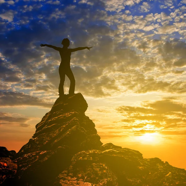 Meisje silhouet blijven op de top van een berg op de achtergrond van een zonsondergang — Stockfoto