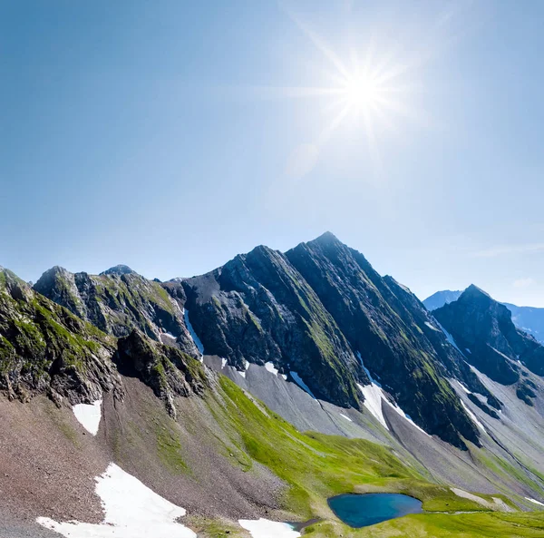 Cume de montanha em uma neve abaixo de um sol brilhante — Fotografia de Stock