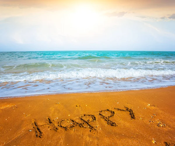 Praia do mar ao pôr do sol com o sinal palavra feliz — Fotografia de Stock