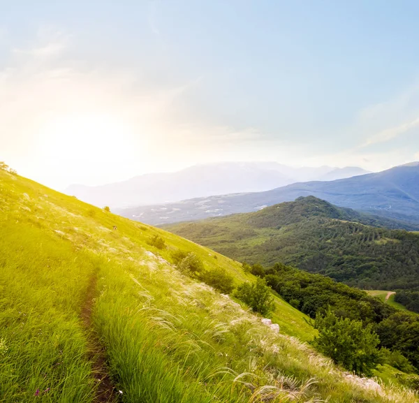 Pôr do sol sobre encosta montanha verde — Fotografia de Stock