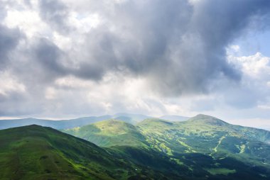 yeşil dağların bir bulutlu gökyüzü altında