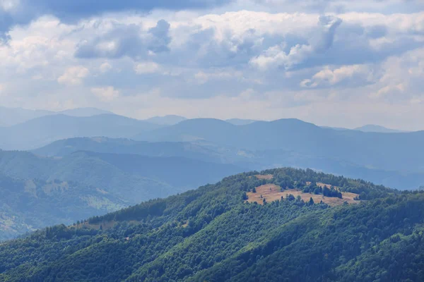 Yeşil dağ sırtı bir bulutlu gökyüzü altında