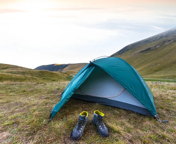 Gröna turistiska tält och par stövlar på solnedgången — Stockfoto