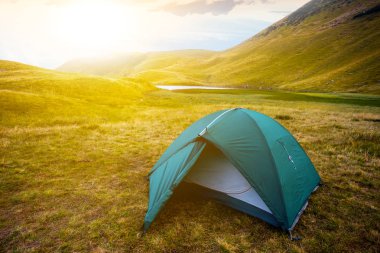 gün batımında dağlar arasında yeşil turistik çadır