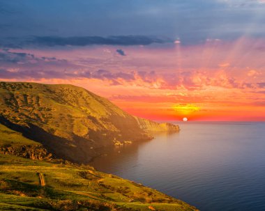 sessiz deniz gün batımında kayalık sahil ile defne