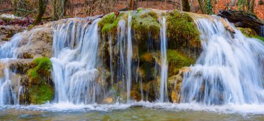 Dağ nehrinde güzel, geniş bir şelale, arka planda