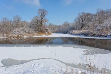 Ormanda donmuş bir nehir, nehir kıyısında eriyen buz.