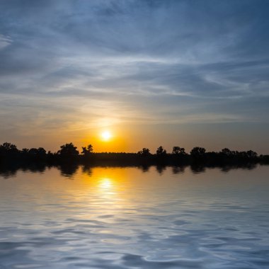 Sessiz bir göle yansıyan dramatik gün batımı, güzel bir alacakaranlık arka planı.