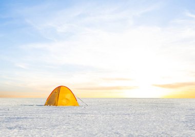 Sarı turistik çadır gün batımında karla kaplı düzlüklerde