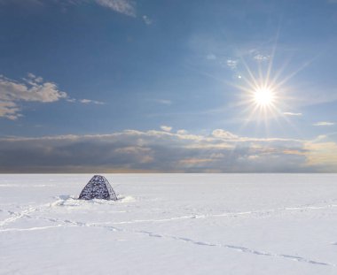 Güneşli bir günde, karla kaplı ovaların arasında turistik çadır.