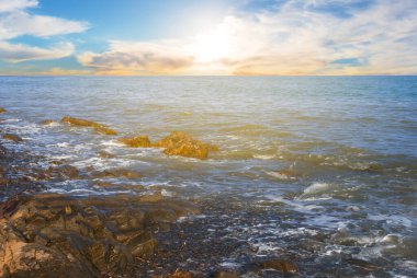 Sahilde taşlı deniz koyunda gün batımında, dışarıda tatil sahnesinde.