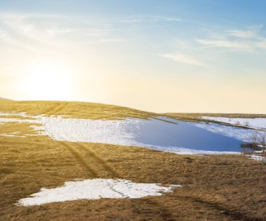 Günbatımında çimenli ve karlı tepeler, ilkbahar başları dağ manzarası