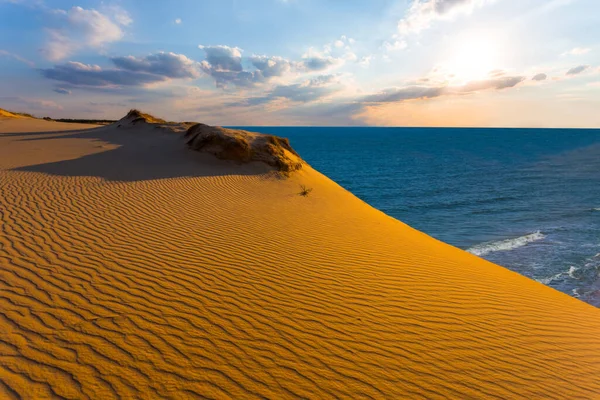 Günbatımında bir deniz koyunun üzerindeki kumlu kum tepeciği, akşam deniz manzarası