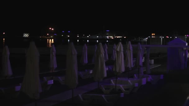 Lento panorama de playa por la noche con puerto marítimo — Vídeos de Stock