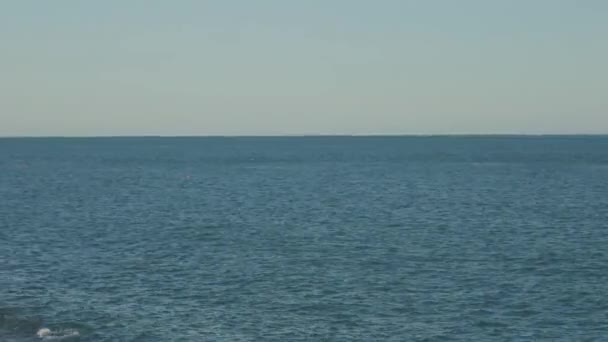 Langzame panorama van de rotsachtige kust met strand en toeristen. — Stockvideo