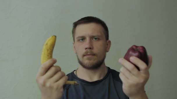 Hombre eligiendo entre manzana y plátano . — Vídeos de Stock