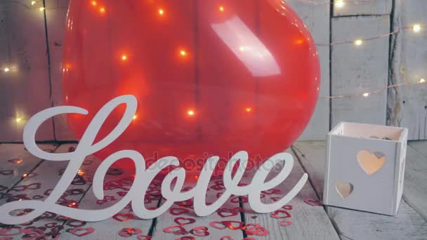 Slow close-up slide shot of Love sign with red hearts, lights and red baloon on background. Valentines day.