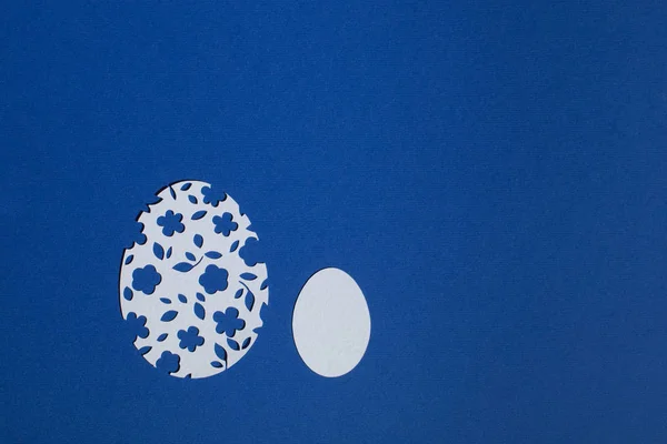 Klasik mavi arka planda kağıttan kesilmiş Paskalya yumurtaları.
