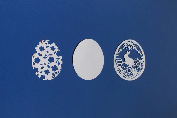 Klasik mavi arka planda kağıttan kesilmiş Paskalya yumurtaları.
