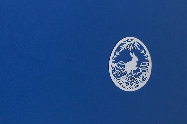 Klasik mavi arka planda kağıttan kesilmiş Paskalya yumurtaları.