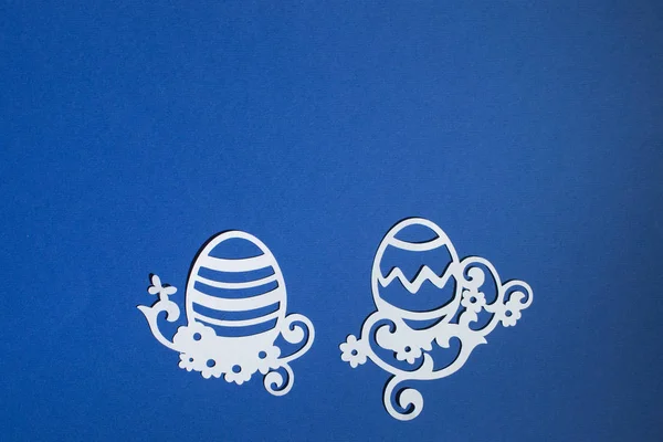 Klasik mavi arka planda kağıttan kesilmiş Paskalya yumurtaları.