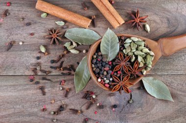 Geleneksel baharatlar. Kuru karanfiller, anason yıldızları, kakule, ahşap kaşıkta biber ve defne yaprağı karışımı..