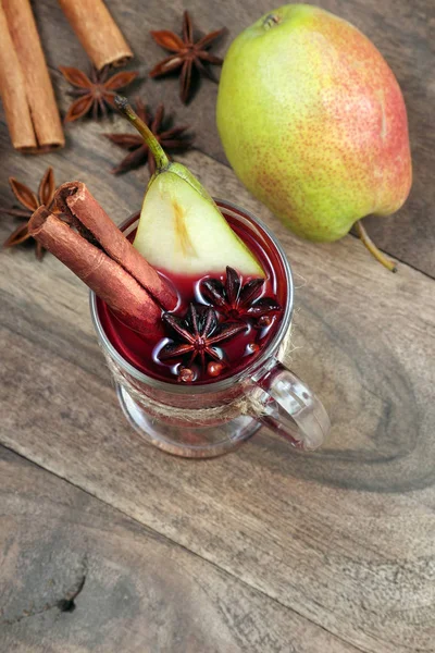 Christmas background. mulled wine and ripe pears. cup of mulled wine and traditional spices on a wooden table close-up