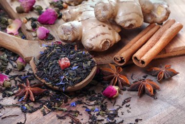 Bir fincan taze çay ve baharat. Tahta bir masada siyah karıştırılmış çay, zencefil, anason ve tarçın. Tahta kaşıkta çay ve geleneksel baharatlar.