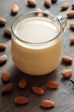 Tahta bir masanın üzerindeki cam bardakta badem sütü. badem ve süt