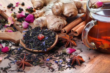 Bir fincan taze çay ve baharat. Tahta bir masada siyah karıştırılmış çay, zencefil, anason ve tarçın. Tahta kaşıkta çay ve geleneksel baharatlar.