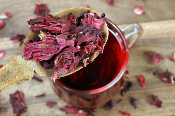 hibiscus tea. dry hibiscus petals in a wooden spoon close up. cup of hibiscus tea.