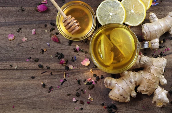 honey, lemon, ginger and a cup of tea with lemon on a wooden table. traditional cold remedies. top view. copy spaces