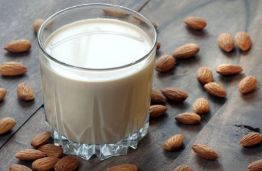 Tahta bir masanın üzerindeki bardakta badem sütü. badem ve süt.