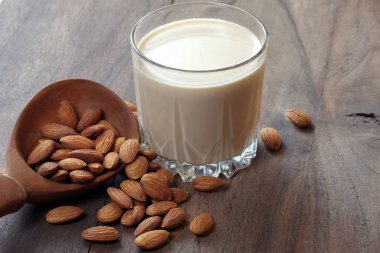 Tahta bir masada bardakta badem sütü. Tahta kaşıkta badem ve bir bardak badem sütü.