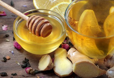 Bal, limon, zencefil ve ahşap bir masada limonlu bir fincan çay. Geleneksel soğuk algınlığı ilaçları