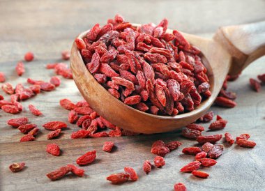 Tahta bir kepçenin içindeki goji üzümleri. Cam bir kavanozda kurutulmuş goji.